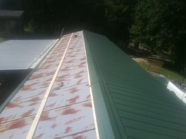 Old rusted panels beside newly installed green metal roofing — Wind Damage Roof Repair by Roofing Brothers in East Greenville