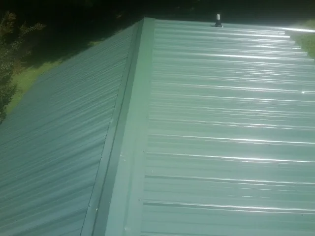 New green metal panels meeting at the ridge of a roof — Flat Roof Repair work by our crew in East Greenville