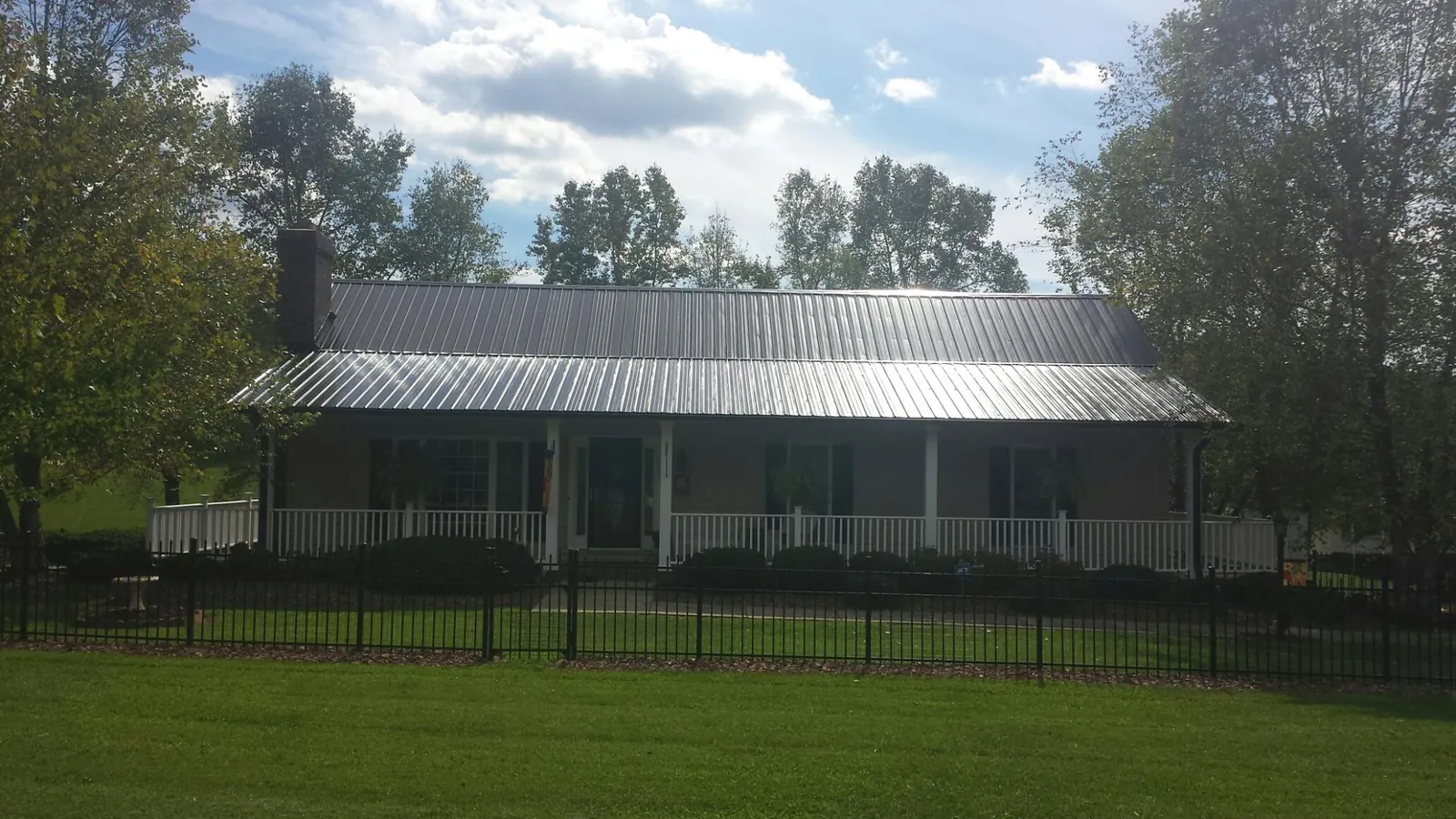 Gray metal roof on a brick ranch with a full width front porch — Gutter Guard Installation work by our crew in East Greenville