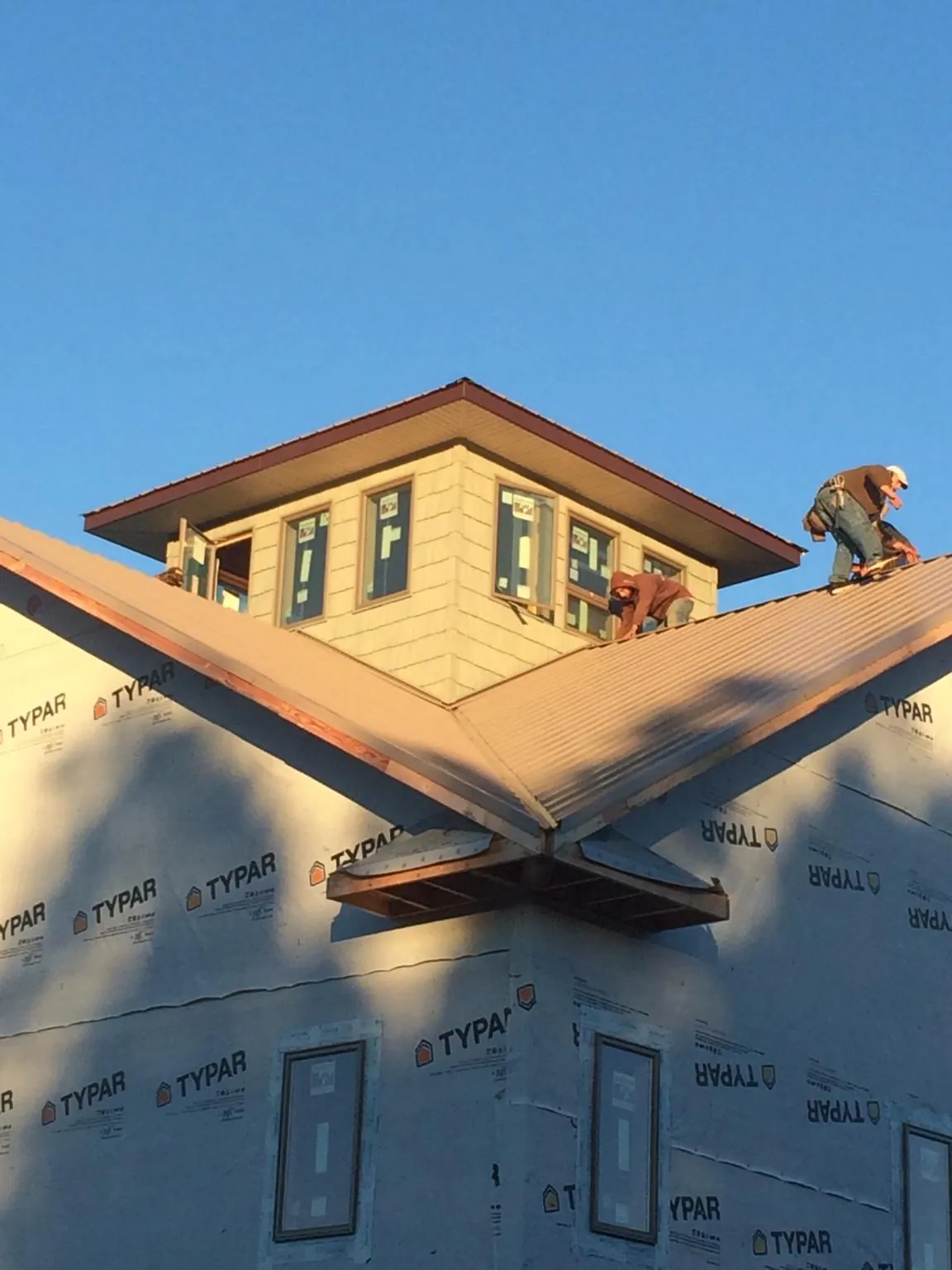 Roofers working around a rooftop cupola on a new metal roof at sunset — Roof Waterproofing in East Greenville by Roofing Brothers